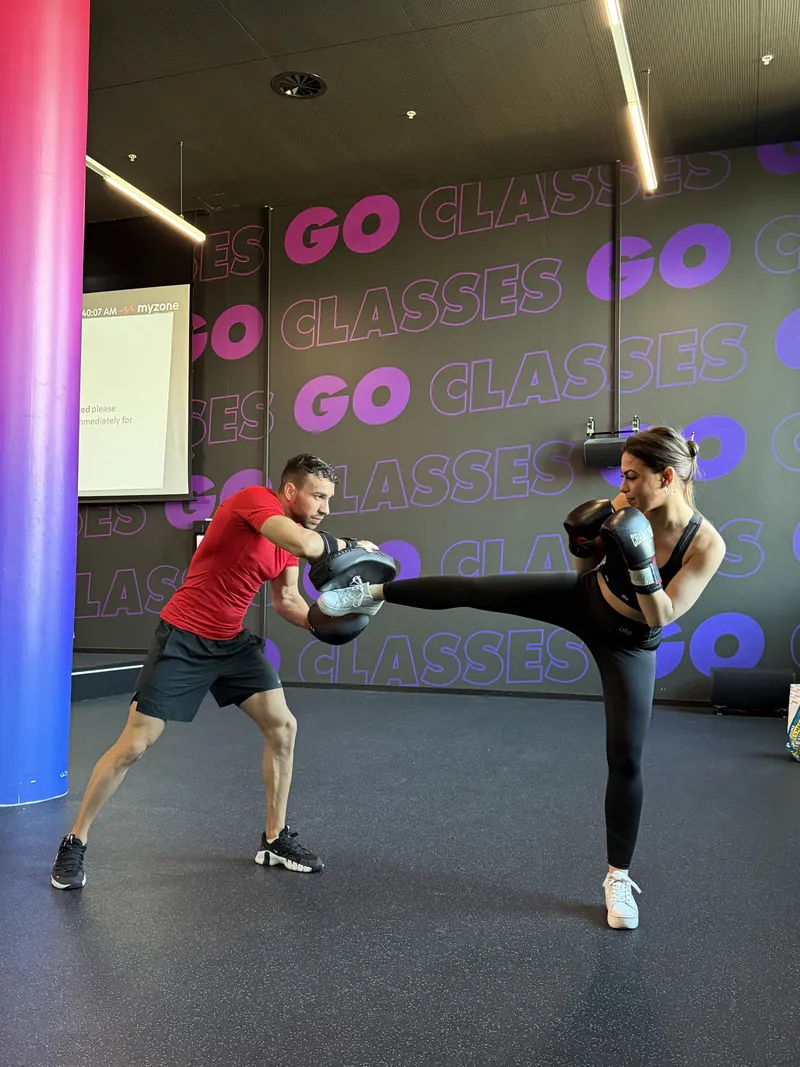 Coup de pied travaillé sur les pads tenus par Samy, coach de boxe à Genève