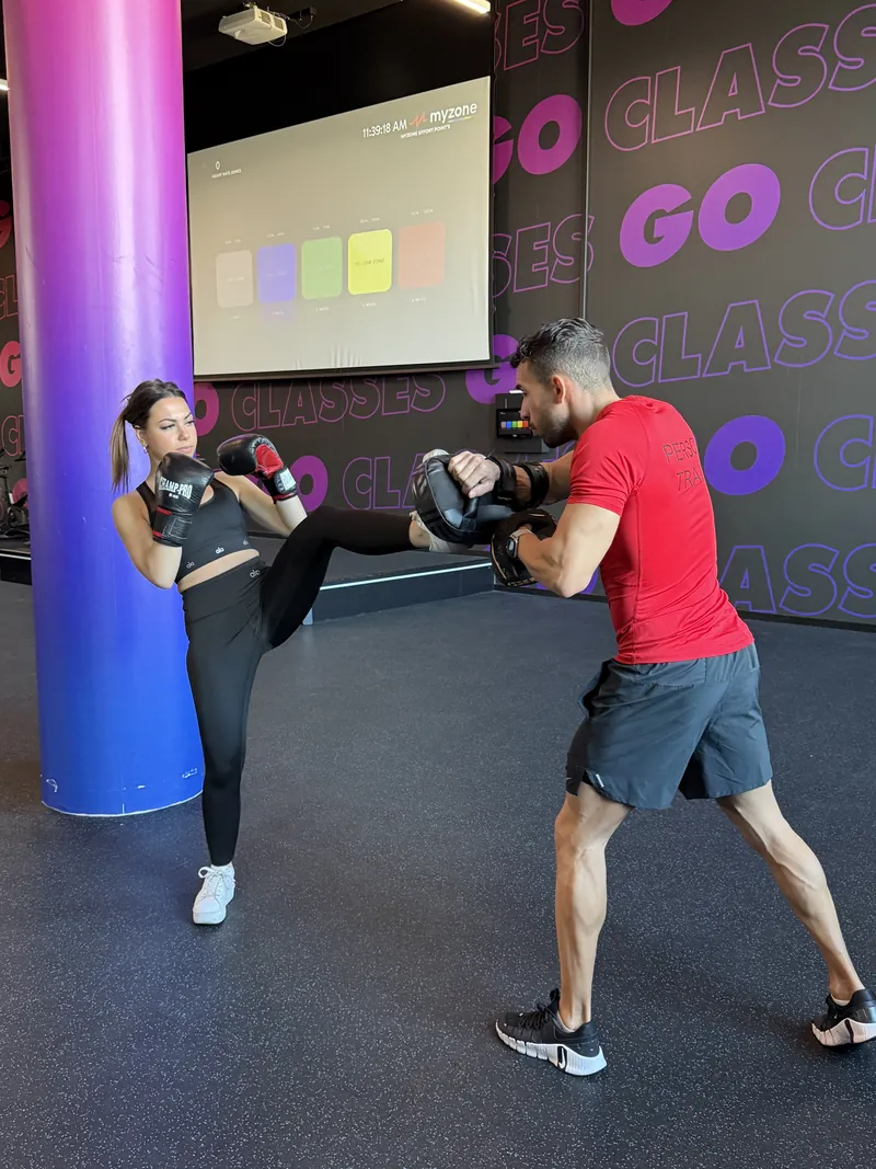 Élève en plein coup de pied sur un bouclier tenu par Samy pendant un cours de boxe