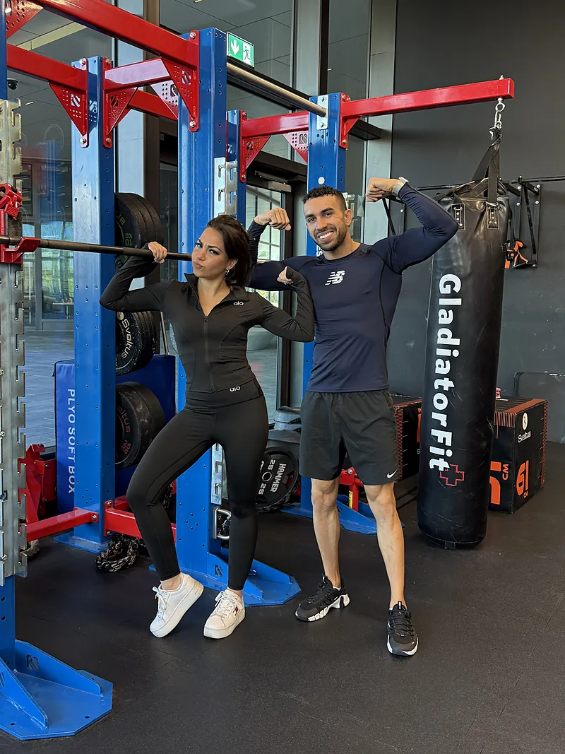 Samy et une cliente prennent la pose devant un rack de musculation