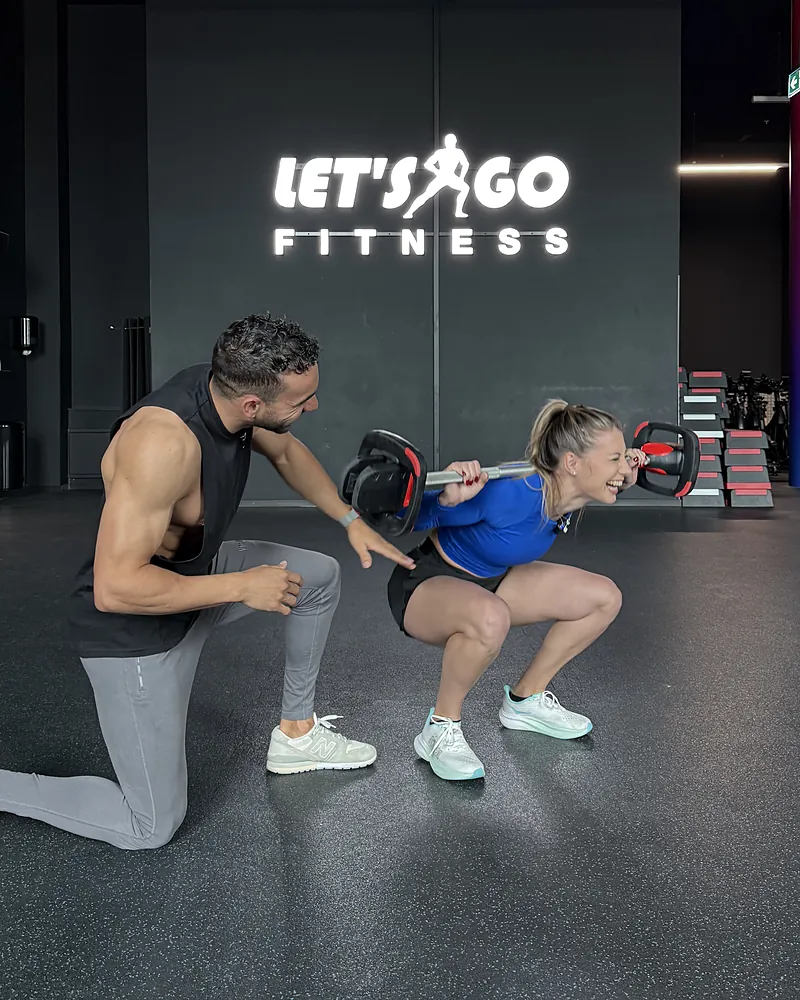 Samy corrige le squat d’une cliente chez Let’s Go Fitness